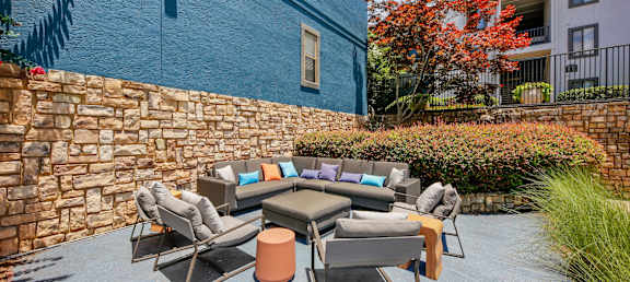 A patio with a table and chairs is surrounded by a stone wall.