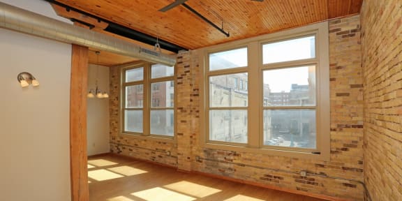 an empty room with a brick wall and large windows