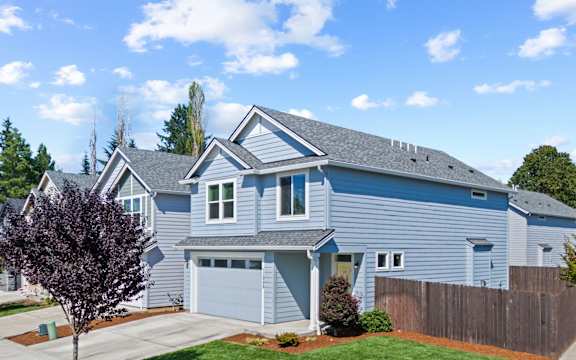 A blue house with a grey roof and a brown fence.