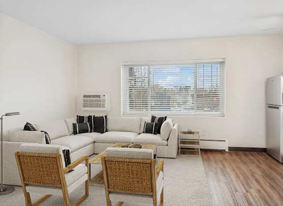 A living room with a couch, chairs, and a window.