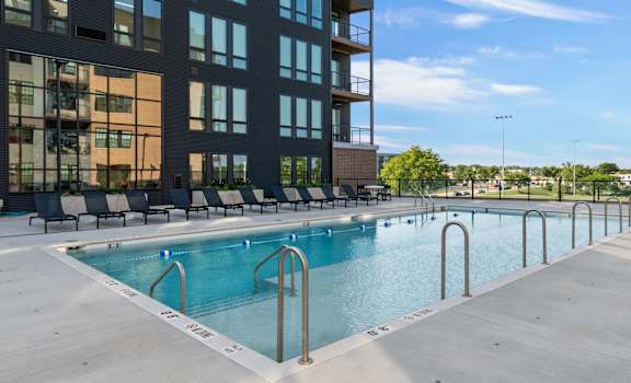 a swimming pool with chairs in front of a building