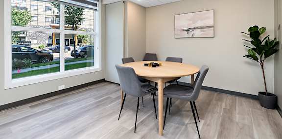 A conference room with a table, chairs, and a plant.