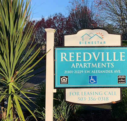 A sign for Reedville Apartments stands in front of a building.