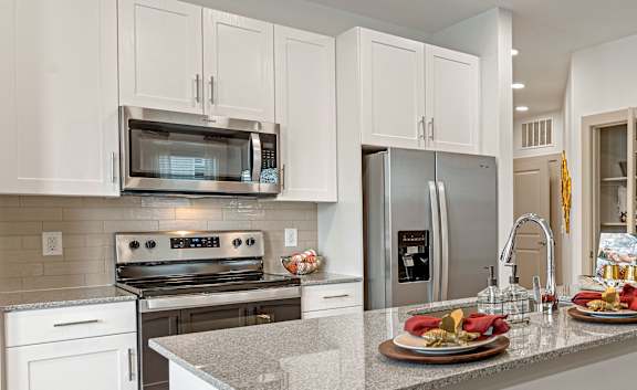 A kitchen with white cabinets and a counter with food on it.