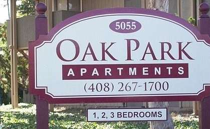 a sign for oak park apartments in front of a house