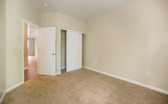 an empty bedroom with two doors and a carpeted floor