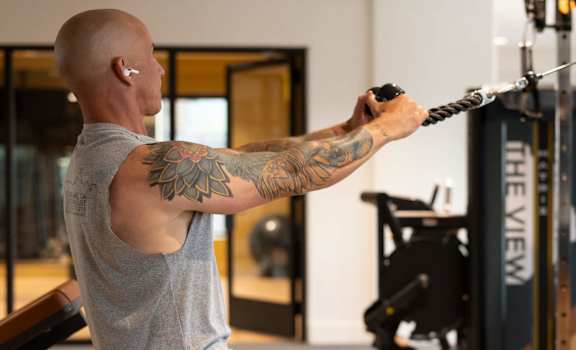 A man with a tattoo on his arm is working out in a gym.