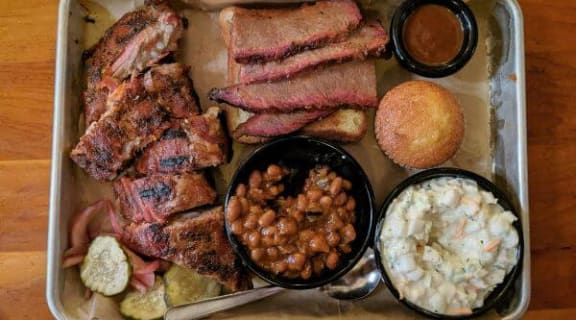 a tray of food with meat and sides on a table