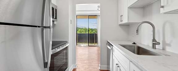 A kitchen with white cabinets and a stainless steel refrigerator.