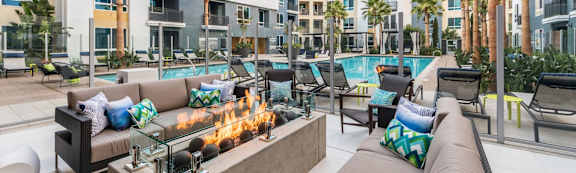 A modern outdoor seating area with a fire pit in the middle.