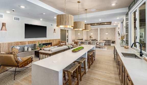 A modern kitchen with a long island and wooden chairs.