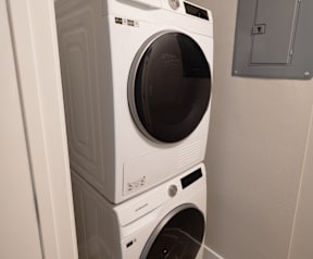 A white front load washing machine is stacked on top of another white front load washing machine.