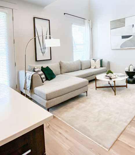 A modern living room with a white couch, a black chair, and a wooden cabinet.