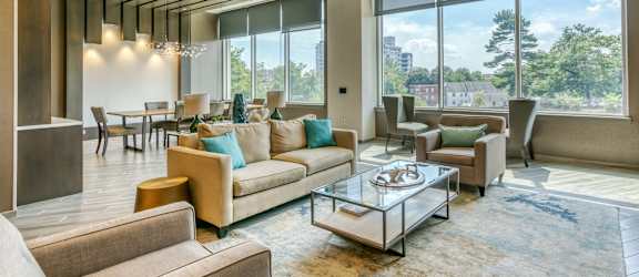 a living room with couches and chairs and large windows