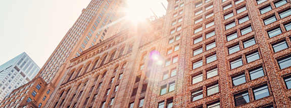 A tall red brick building with the sun shining through the windows.