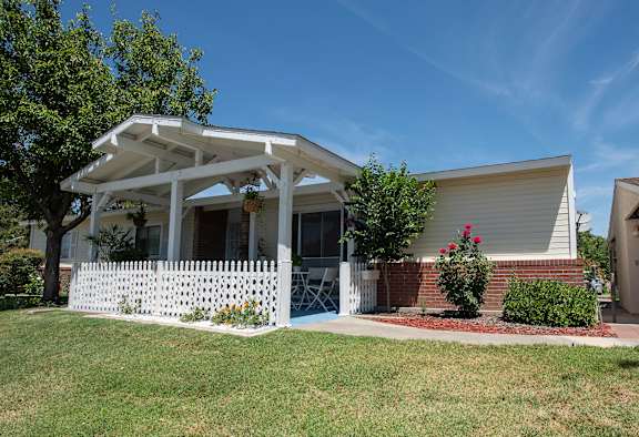 a white house with a lawn and a white picket fence at Castle Vista Senior Duplex Community, Atwater, California