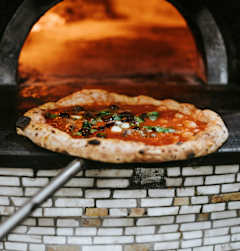 A pizza is being cooked in a brick oven.