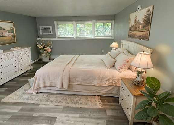 A bedroom with a bed, chair, and lamp.