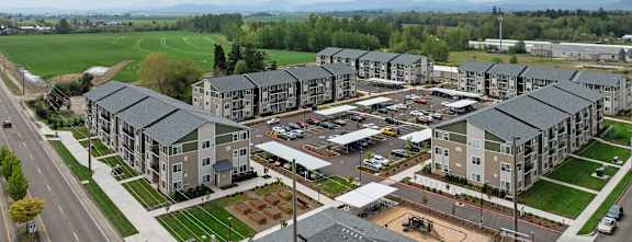 A large apartment complex with a parking lot in front.