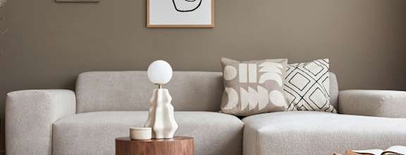A living room with a grey sofa, a wooden table, and a white lamp.