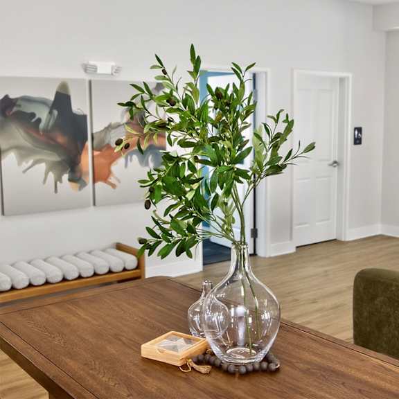 A cozy living room with a white sofa, a wooden coffee table, and potted plants.