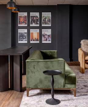 A green chair with a black stool in front of it.