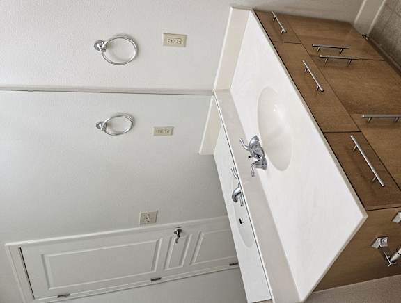 A white sink is installed in a wooden cabinet.