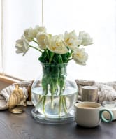 A vase filled with fresh white flowers placed on a table, adding a touch of elegance to the space.