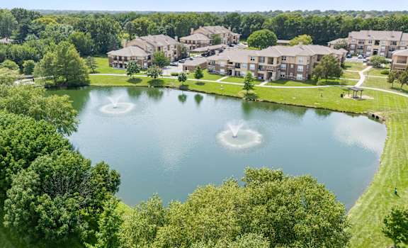 A bird's eye view of a lake surrounded by green trees and buildings. at Stonepost Lakeside Apartment Homes, Olathe, 66062