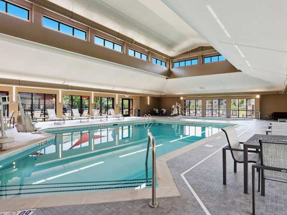 A large indoor swimming pool with lounge chairs and a metal pole.