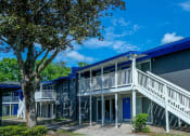 Thumbnail 20 of 23 - Exterior shot of Mandarin Bay Apartments in 32257. Building is two stories with blue-grey brick, blue roof, and white railed staircases