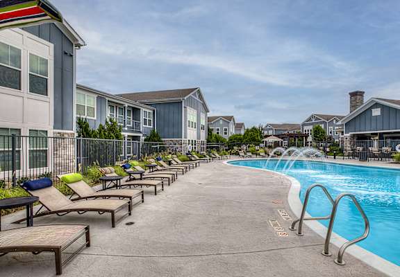 A pool area with sun loungers and a fence.