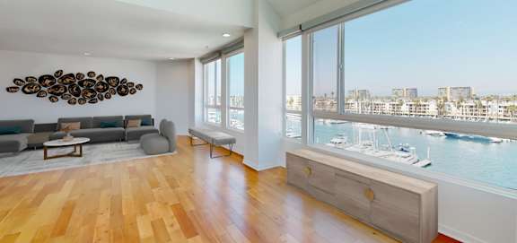 A living room with a view of the water and boats. at Esprit Apartments, Marina del Rey, CA