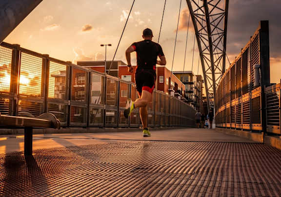 A man is walking on a bridge with a beautiful sunset in the background.