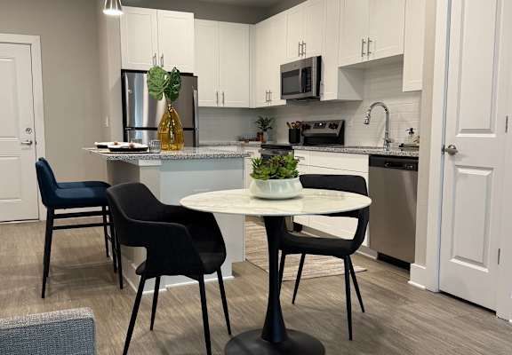 A kitchen with a table and chairs.