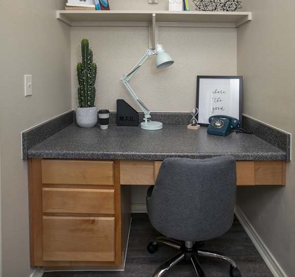 A small office with a desk, chair, and shelves.