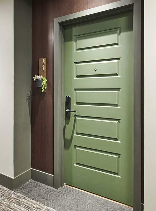 A green door with a handle and a sign on the wall.
