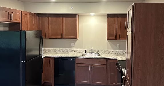 a kitchen with wooden cabinets and a black refrigerator