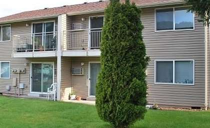 A large apartment building with a tree in front.