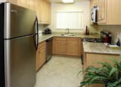 Thumbnail 5 of 22 - A kitchen with a refrigerator on the left and a microwave on the right.