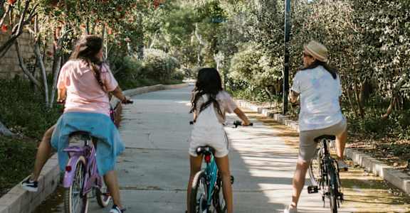 three girls riding bikes down a street