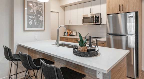 A modern kitchen with a white countertop and stainless steel appliances.at Vista Apartments at Edgemont, Alberta