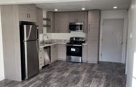 A kitchen with a refrigerator, microwave, oven, and sink.