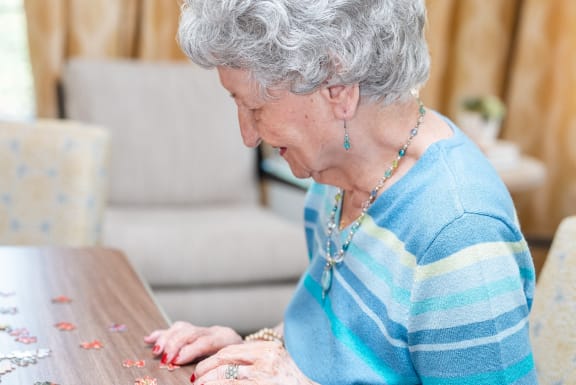 an older woman sitting at a table looking at a piece of paper