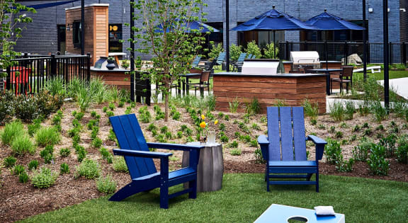 a yard with two blue chairs and a table and an apartment building in the background at Dey & Bergen, Harrison, 07029