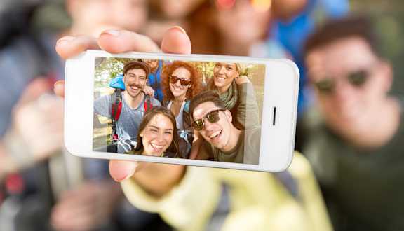 A person is holding a smartphone displaying a photo of a group of people.