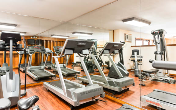 a gym with rows of treadmills and other exercise equipment at Village Pointe Apartments, Northridge, CA, 91325