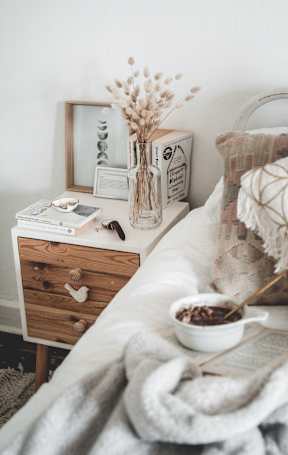 Bedroom featuring a bed and a nightstand with a vase of flowers.