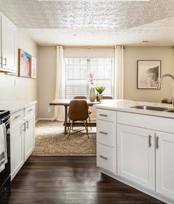 Fairway Lakes Apartments - Kitchen with White Cabinets, Wood Style Flooring and Granite Countertops