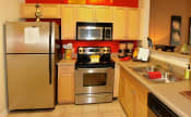 Thumbnail 15 of 36 - a kitchen with stainless steel appliances and wooden cabinets at Chester Village Green Apartments, Chester, VA, 23831